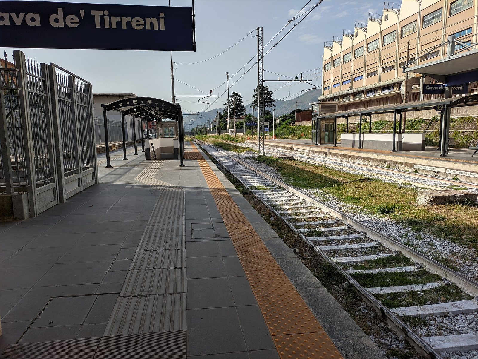 Banchina e binari della stazione ferroviaria di Cava de' Tirreni con il cartello del nome
